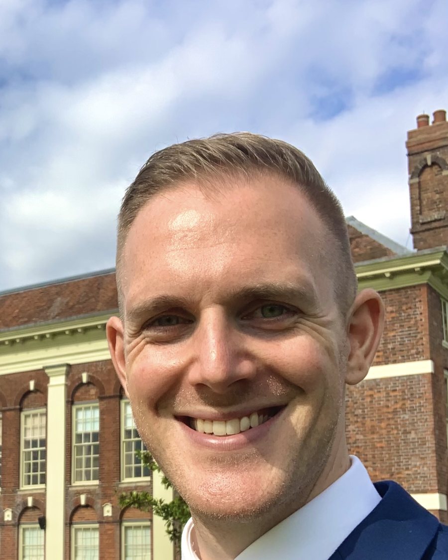 Steve, owner of Keystone Digital, in a navy suit smiling outdoors in front of a red-brick building